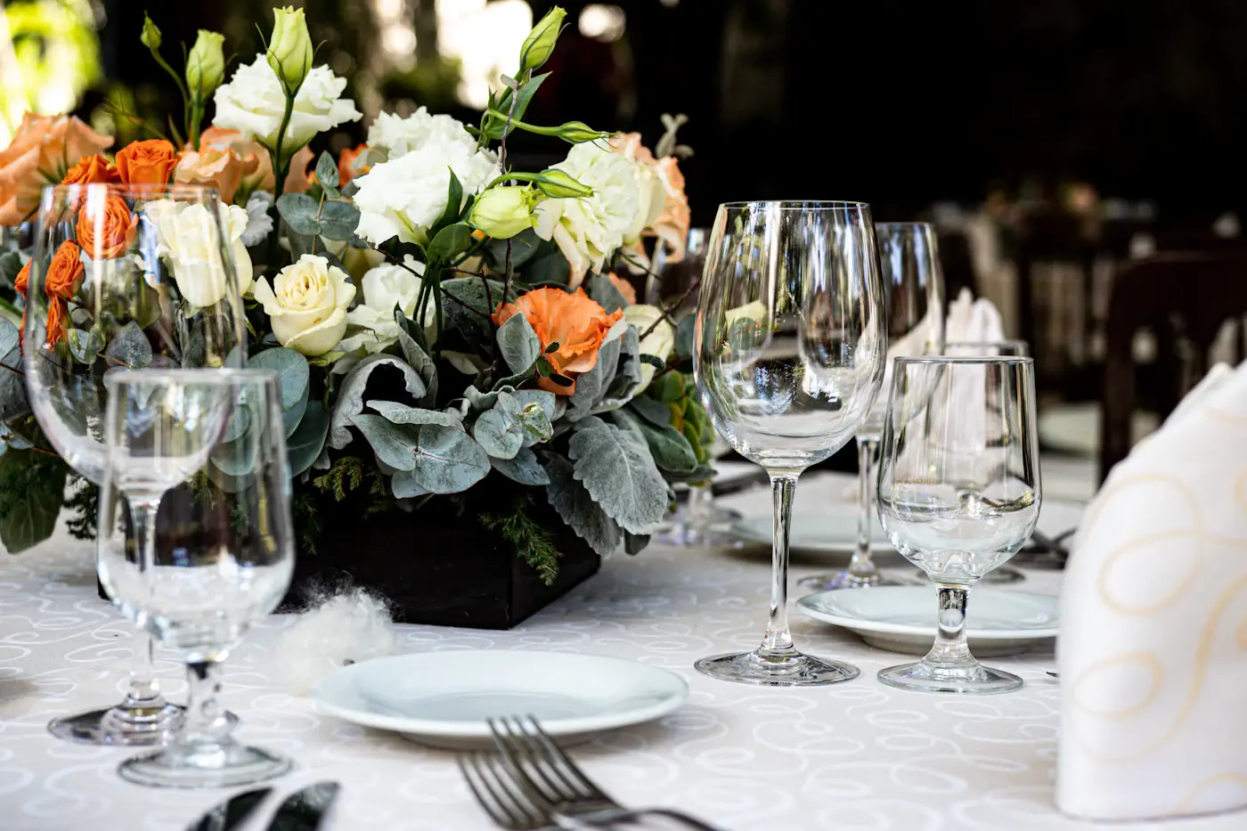 Mesa de recepção posta com flores brancas e alaranjadas e taças.